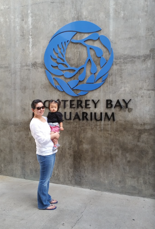 A family photo in front of the Monterey Bay Aquarium sign